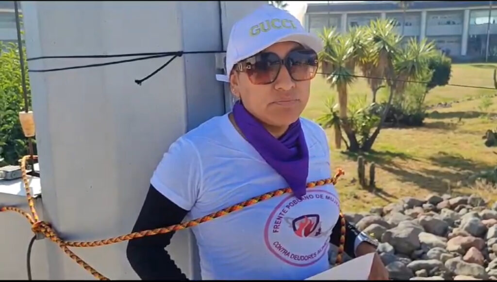 Madre se amarra en asta bandera en Ciudad Judicial de Puebla exigiendo justicia para su hija